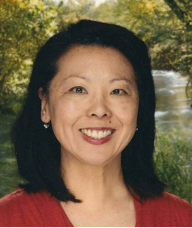 A woman smiles in a portrait with trees and a waterfall in the background