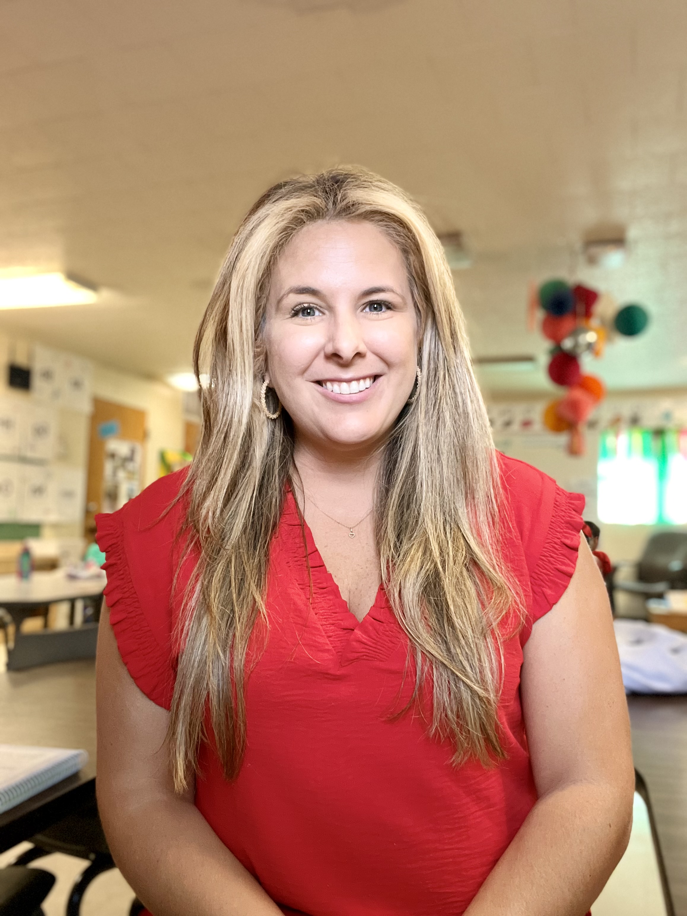 A woman poses for a portrait in a decorated classroom