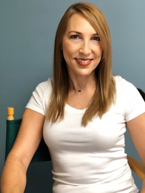 A woman sits in a chair and faces the camera