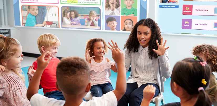 A woman leads a group of young children in an interactive activity in a classroom