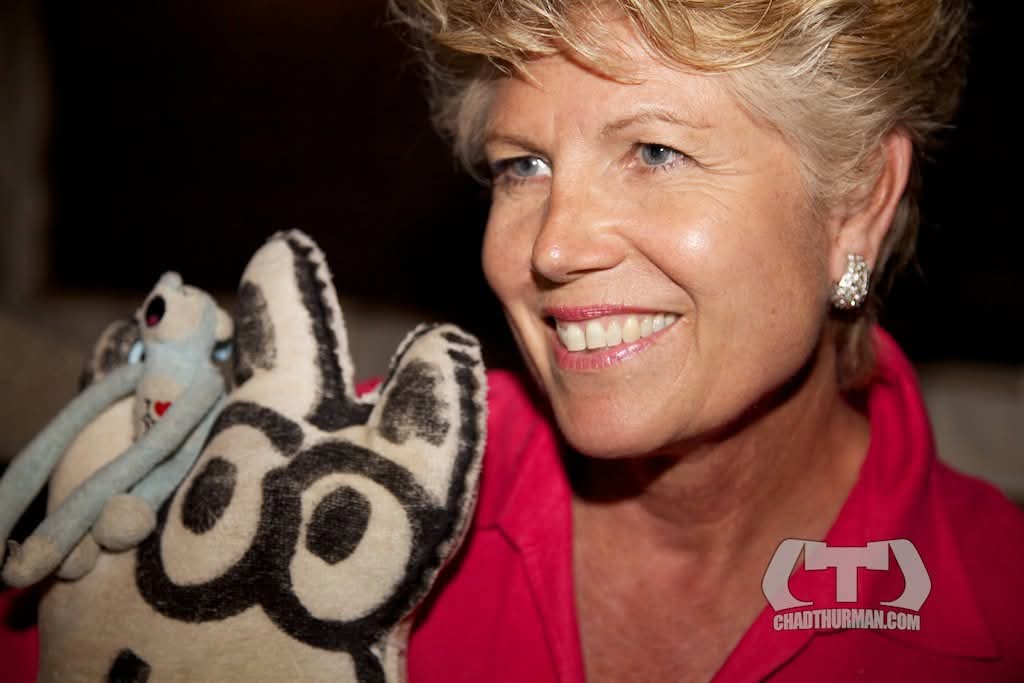 A woman holds two small stuffed animal toys close to her face