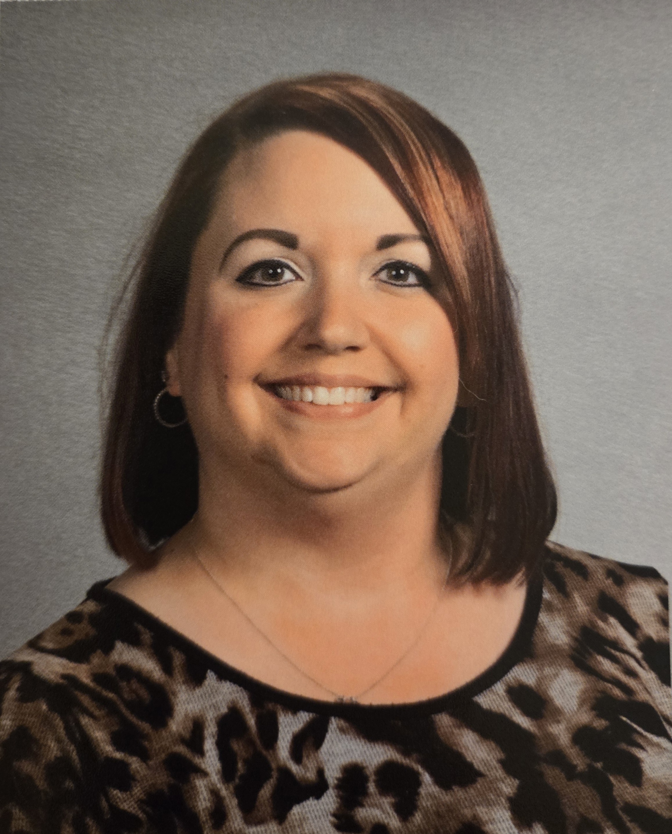 A woman faces the camera in a formal portrait against a neutral background