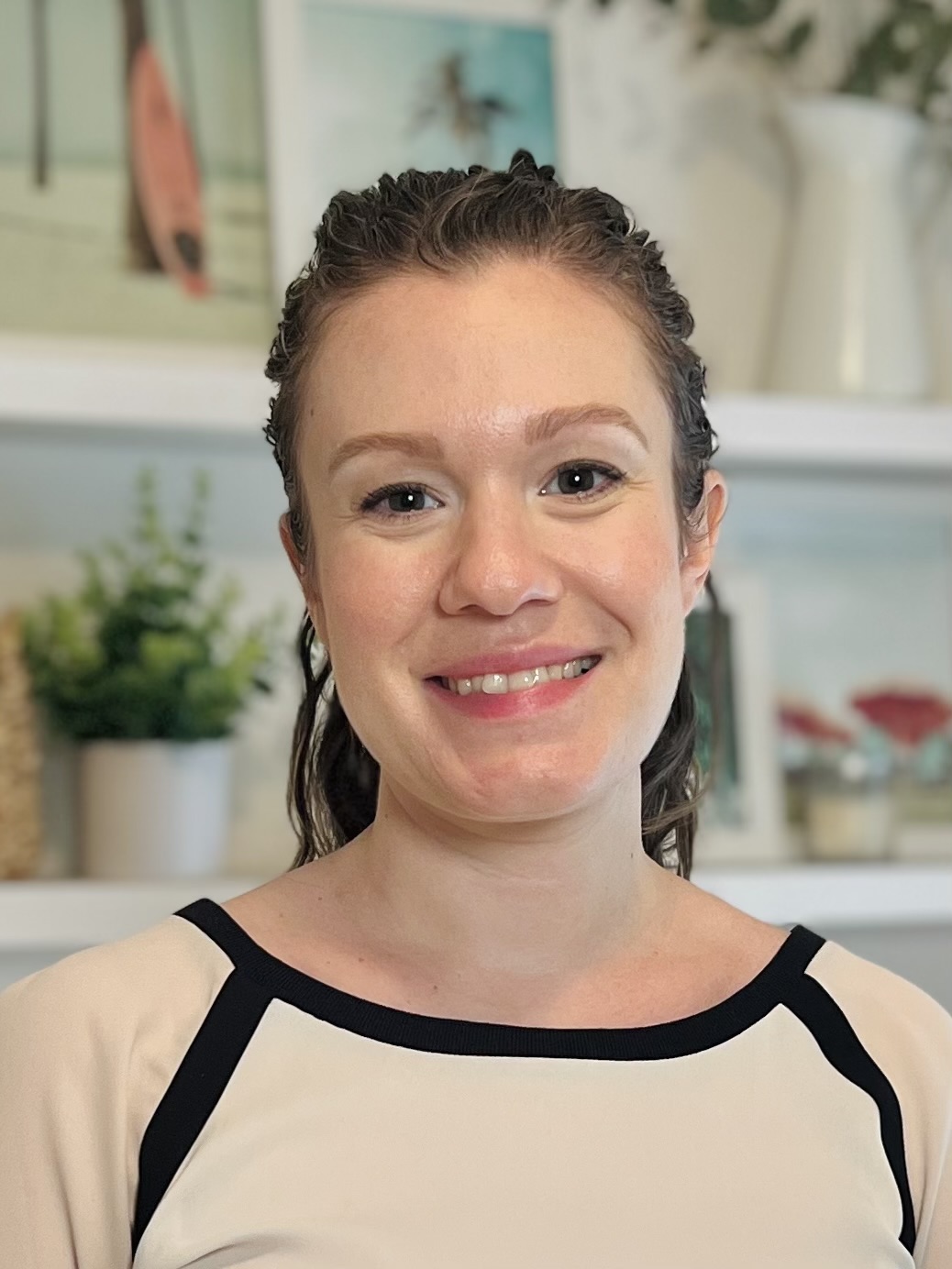 A woman faces the camera with her hair pulled back