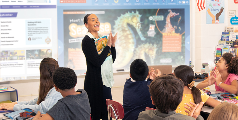 A person holds a book and leads a classroom lesson on seahorses for a group of students