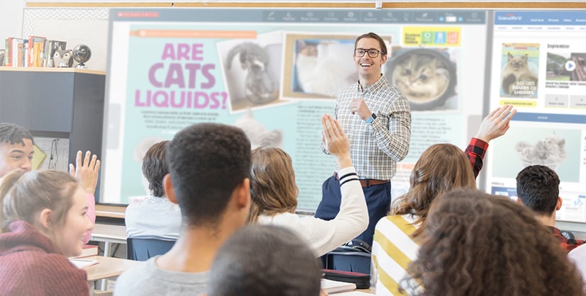 A man leads a classroom lesson on Are Cats Liquids? as students raise their hands