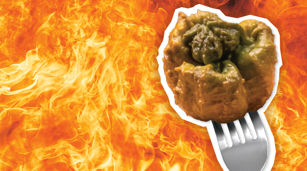 Image of the Pepper X on a fork against backdrop of flames