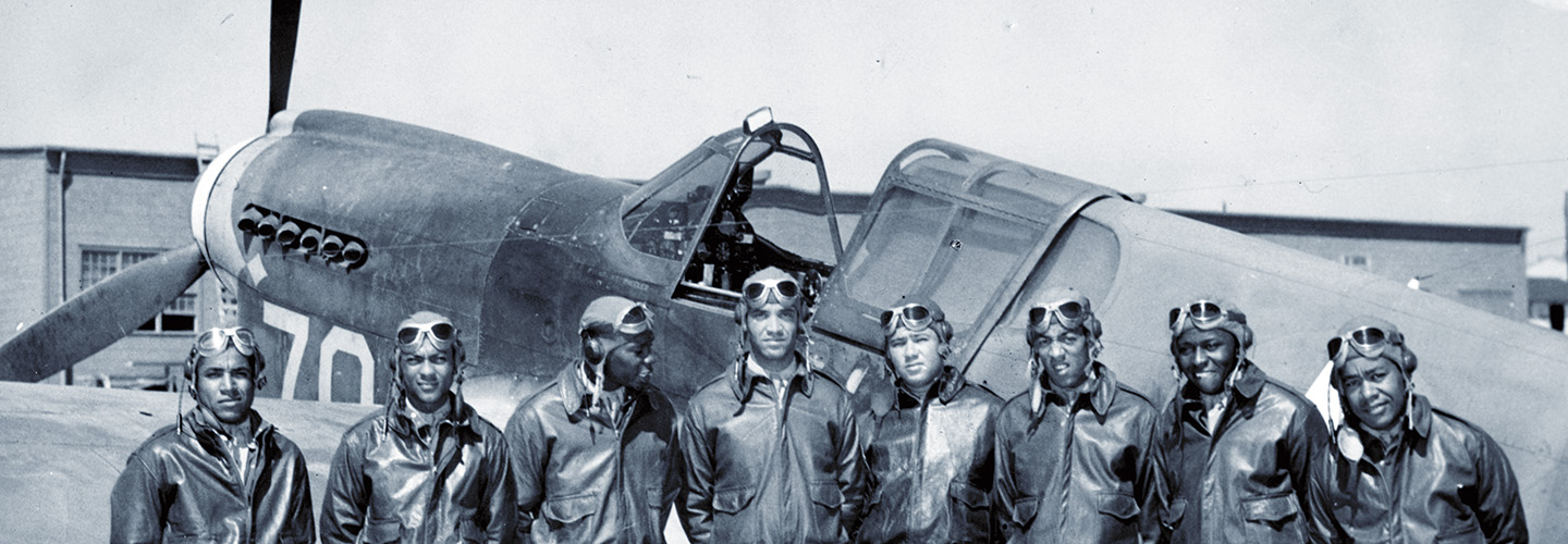 Black & white photo of air officials posing in front of a plane